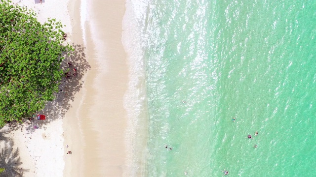 素林海滩鸟瞰图，普吉岛，泰国，素林海滩是普吉岛一个非常著名的旅游目的地，热带沙滩与绿松石清澈的水，游客在海滩上和五颜六色的雨伞。视频素材