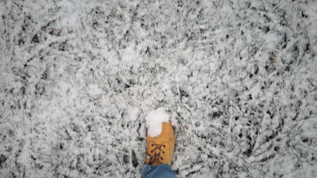 穿着黄色靴子和蓝色裤子的男人的腿走在初雪上视频素材