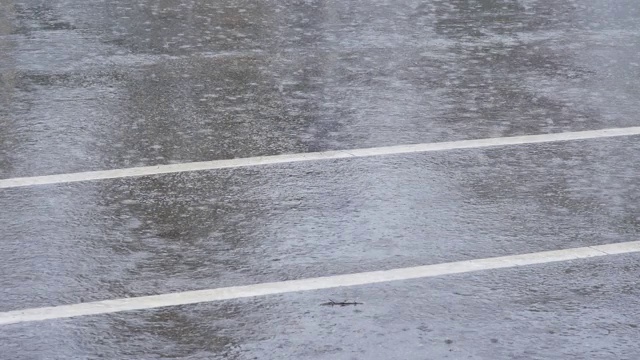 倾盆大雨时，大雨滴落在城市街道上。多雨的天气视频素材