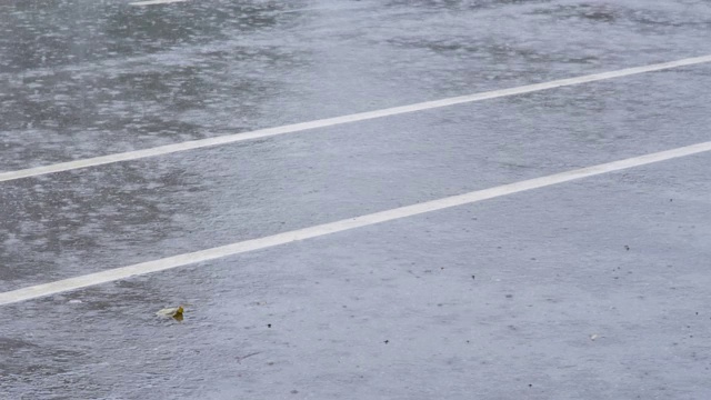 倾盆大雨时，大雨滴落在城市街道上。多雨的天气视频素材