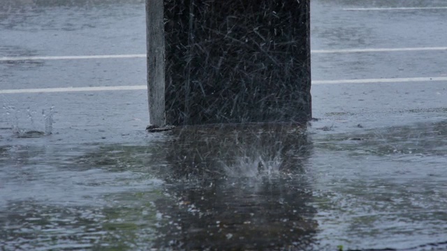 倾盆大雨时，大雨滴落在城市街道上。多雨的天气视频素材