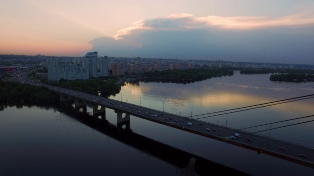 无人机俯瞰悬索桥上的车辆在夜晚的城市景观视频素材