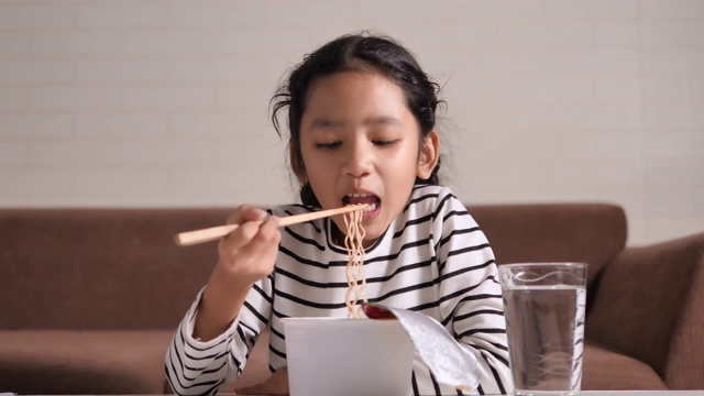 小亚洲女孩吃着热辣的方便面用幸福选择焦点浅景深视频素材