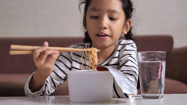 小亚洲女孩吃着热辣的方便面用幸福选择焦点浅景深视频素材