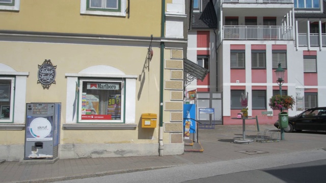 商店和建筑物通往五颜六色的天主教教堂在萨尔茨堡大街，Schladming, Styria，奥地利阿尔卑斯山，奥地利，欧洲视频素材