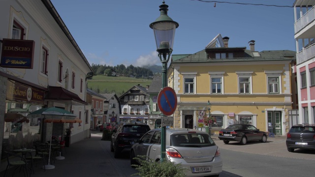 商店和建筑物通往五颜六色的天主教教堂在萨尔茨堡大街，Schladming, Styria，奥地利阿尔卑斯山，奥地利，欧洲视频素材