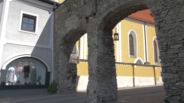 商店和建筑物通往五颜六色的天主教教堂在萨尔茨堡大街，Schladming, Styria，奥地利阿尔卑斯山，奥地利，欧洲视频素材