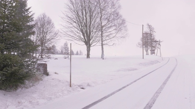 在暴风雪期间有汽车轨道的乡村道路视频素材