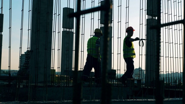 两名工人在建筑工地安装金属建筑。视频素材