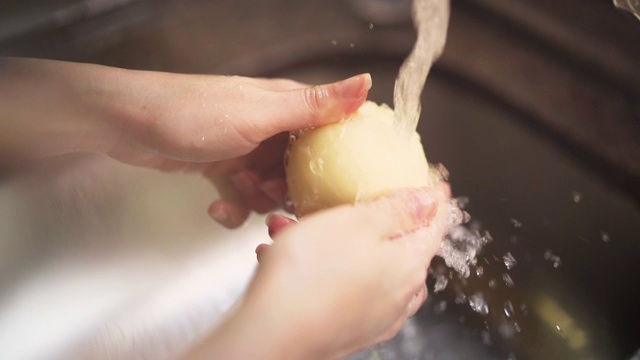 女人的手在厨房水龙头下洗洋葱的慢动作镜头。视频素材