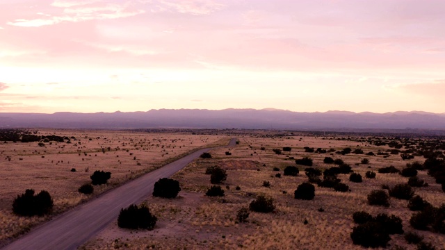 新墨西哥沙漠公路的乡村景象:夕阳下，汽车行驶在一条土路上视频素材