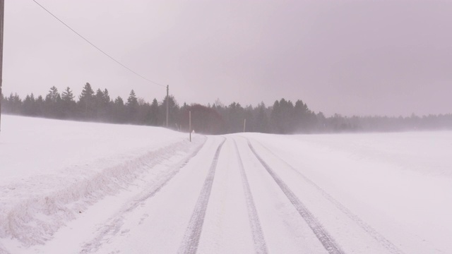 大雪中有车辙的乡村公路上的暴风雪视频素材