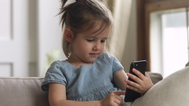 可爱聪明的小女孩拿着手机独自在家视频素材
