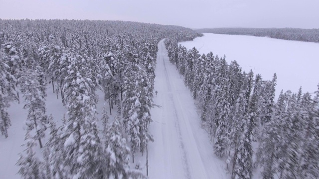 在欧洲芬兰的拉普兰，通过无人机观察被雪覆盖的道路视频素材