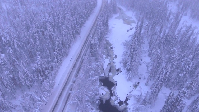 在欧洲芬兰拉普兰的阿阿斯隆波罗附近，冬季被雪覆盖的道路和冰冻的河流视频素材