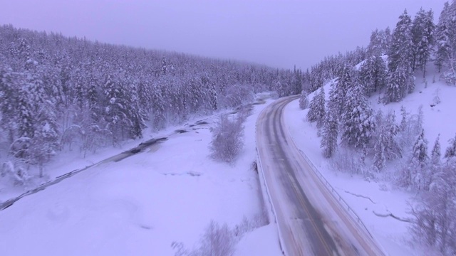 在欧洲芬兰拉普兰的Akaslompolo附近的一条积雪覆盖的道路上行驶的无人机视频素材