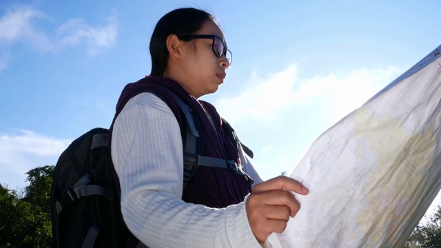 年轻女子旅行者与地图和背包放松户外的自然小径在暑假。徒步旅行生活方式的概念。视频素材