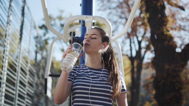 有吸引力的白人女人在运动装准备运动。健康的女孩手里拿着摇酒器。运动和健康的生活方式。运动女孩在一个公园的户外运动场上锻炼。视频素材