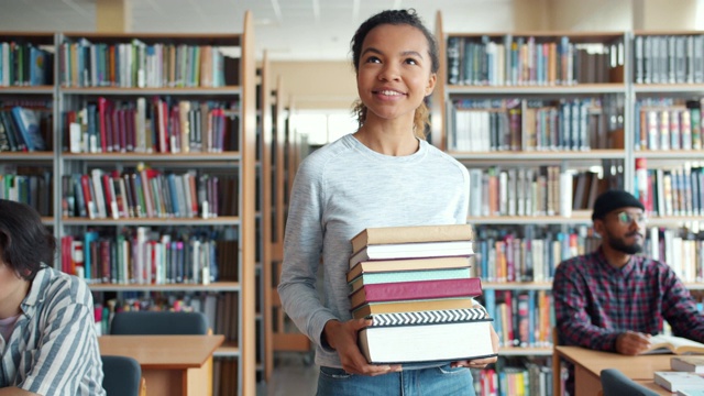 漂亮的混血女学生拿着书微笑着走进图书馆视频素材