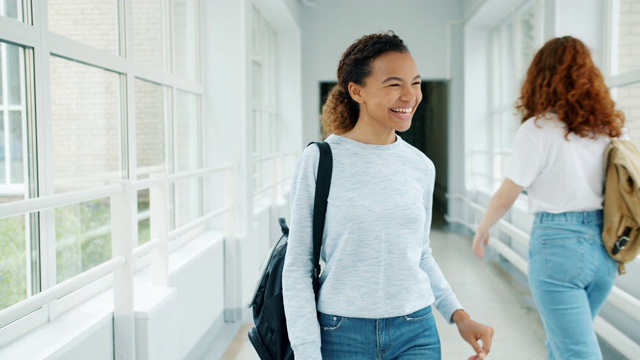 漂亮的非裔美国女学生走在大学大厅问候朋友视频素材