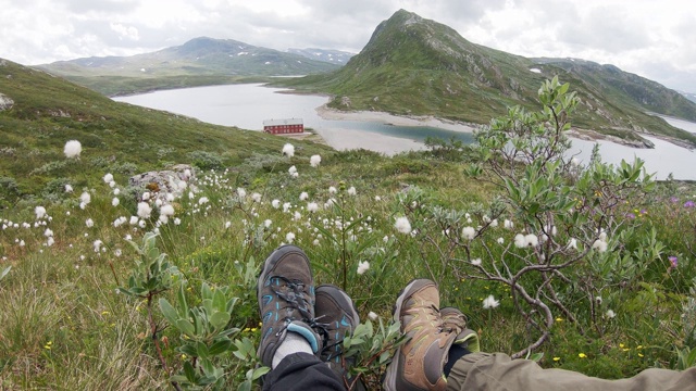 两个旅行者坐在挪威峡湾上方的小山上。视频素材