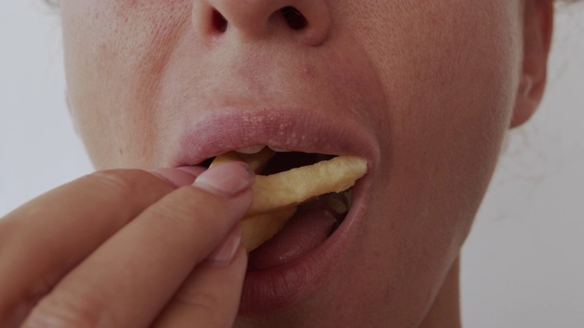 吃薯条的女人，不健康的饮食，闭上嘴唇视频素材