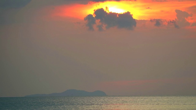 夕阳下，海面剪影，暗红色的云移动过太阳视频素材