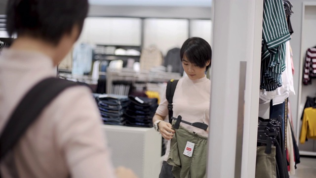 挑选衣服的女人在服装店里照镜子视频素材