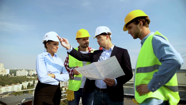 建筑工程师手持建筑图则向工人讲解安全帽视频素材