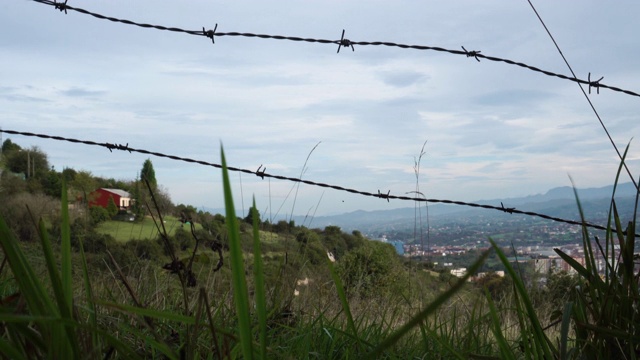 铁丝网栅栏映衬着碧绿的草地、草地和蓝天视频素材