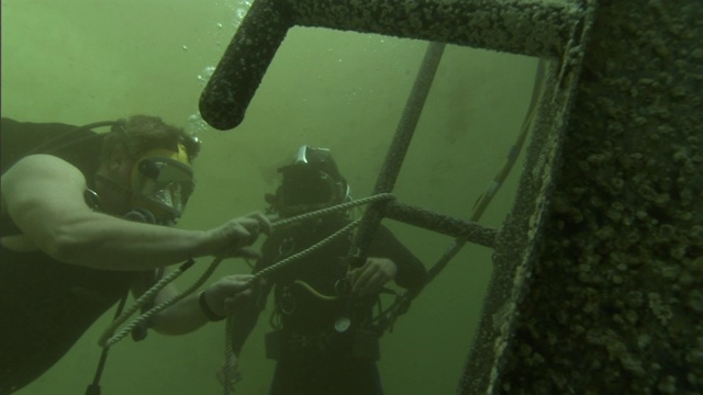 潜水员把绳子系在水下的建筑物上。视频素材