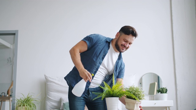 慢镜头微笑的男人洒在花盆里的花照顾植物视频素材