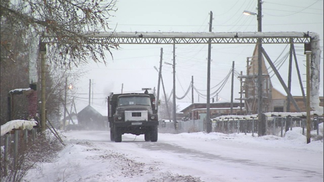 在俄罗斯，一辆卡车在积雪的道路上从一根管道下驶过。视频素材