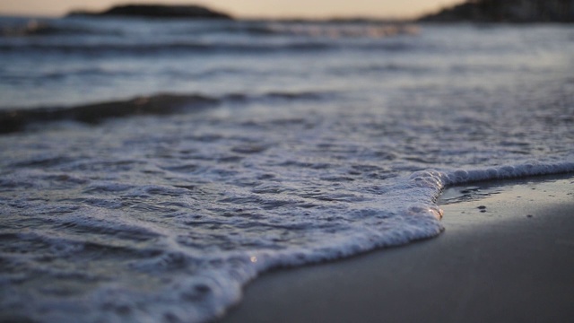 脚在海边的沙滩上留下痕迹，海水冲走了这些痕迹，近处，慢镜头视频素材