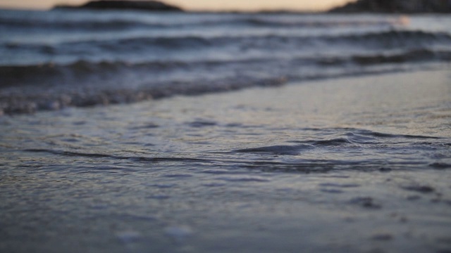 脚在海边的沙滩上留下痕迹，海水冲走了这些痕迹，近处，慢镜头视频素材