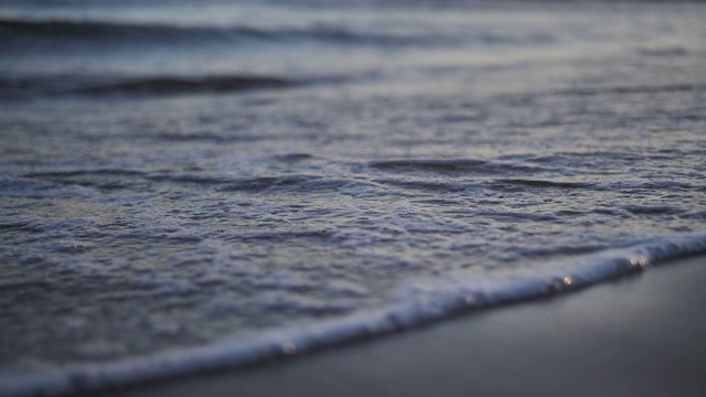 脚在海边的沙滩上留下痕迹，海水冲走了这些痕迹，近处，慢镜头视频素材