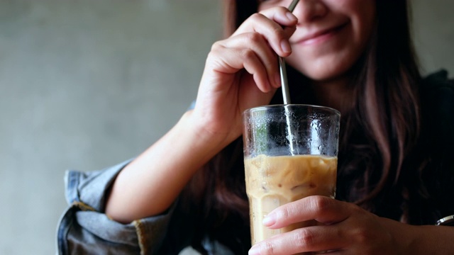 一个女人拿着不锈钢吸管搅拌冰咖啡视频素材