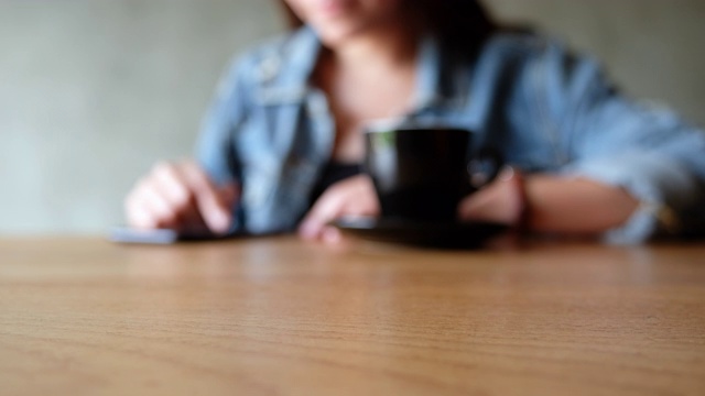 模糊的女人用咖啡杯触摸手机视频素材