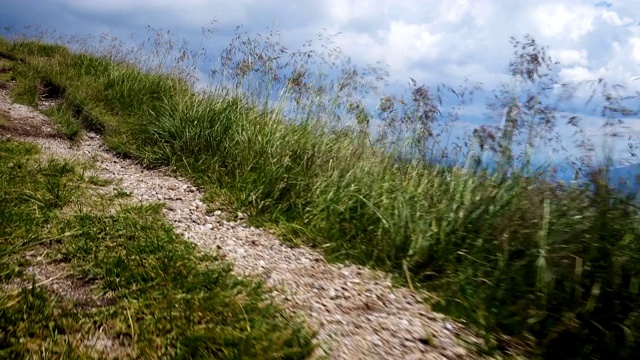 走在空旷的徒步小道上，可以看到远处草地上的小山和羊群视频素材