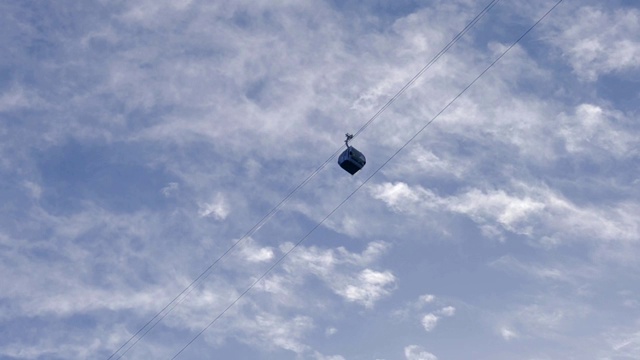 背景是多云的天空，空中缆车沿着绳索移动视频素材