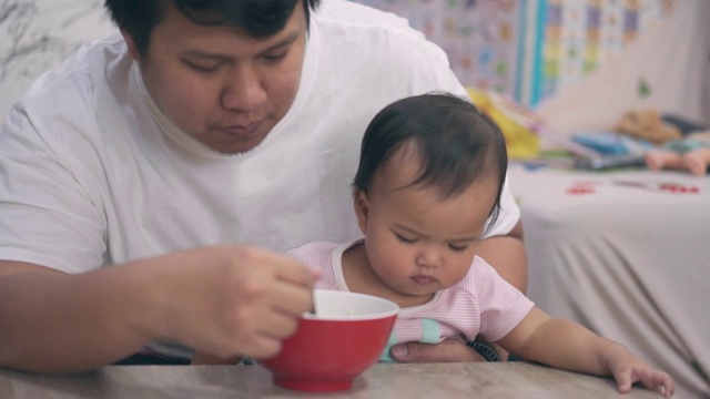 父亲一边吃面条一边照顾女儿视频素材