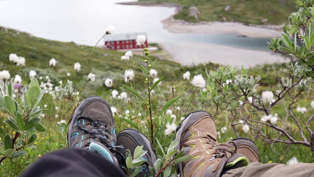 两个旅行者坐在挪威峡湾上方的小山上。视频素材