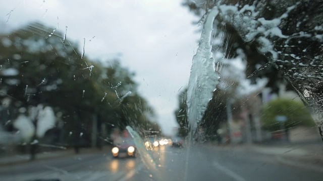 在雨中开车，透过湿漉漉的挡风玻璃看路，而雨刷是开着的视频素材