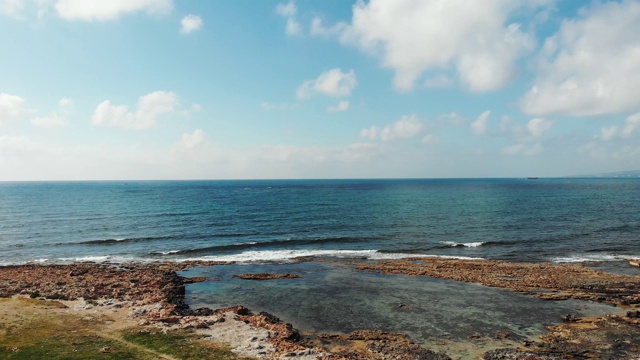 鸟瞰图蓝色的风景大海和岩石海岸与强烈的海浪击打海岸溅起泡沫。视频素材