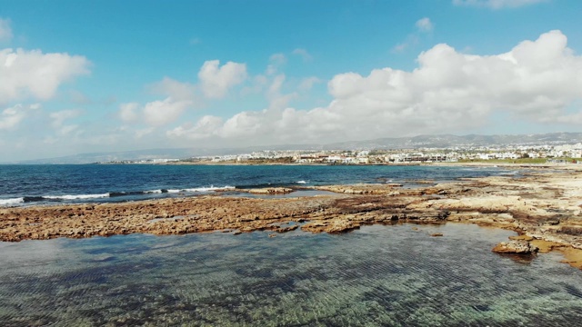 无人机拍摄海浪和平静的海湾。以山脉和城市为背景。海湾里清澈的海水。视频素材