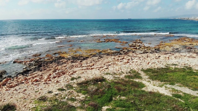 航拍蓝色的海洋和岩石海滩与海浪拍打岩石海岸。塞浦路斯帕福斯海岸线的无人机视图视频素材