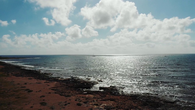 航拍的阳光反射在波浪的海面在日落。海浪拍打着布满岩石的海滩。海洋海岸视频素材