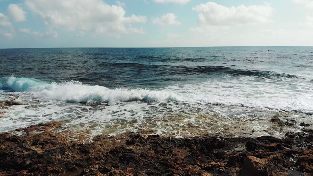 无人机拍摄的强烈海浪撞击岩石海滩的景象。多岩石的海岸，海浪撞击，产生泡沫和水花。视频素材