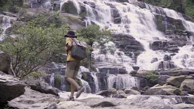 沿着瀑布行走的年轻男性徒步旅行者视频素材