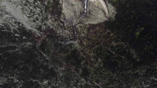 在森林覆盖的黑暗山脉中，无人机从覆盖池塘的大坝中射击小溪(Santa Anita Canyon, California, USA)视频素材